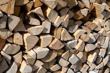 Tightly stacked firewood lies in a large pile. Prepared firewood for heating the house