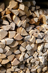 Vertical photo of fresh logs stacked neatly on top of each other. Prepared firewood for heating the house