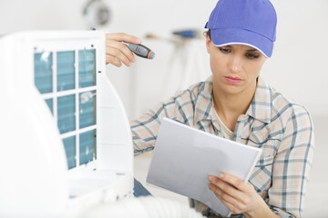 handywoman reading manual about fixing ventilation system