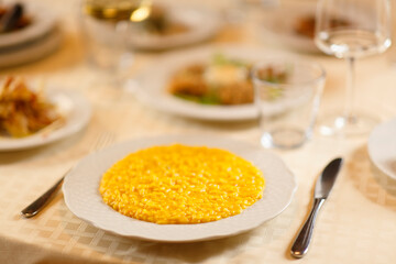 Close up on italian traditional northern food on a restaurant table. Risotto alla milanese.