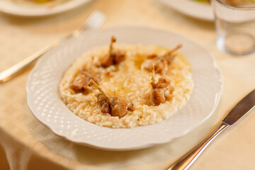 Close up on italian traditional northern food on a restaurant table. Risotto with frogs legs.