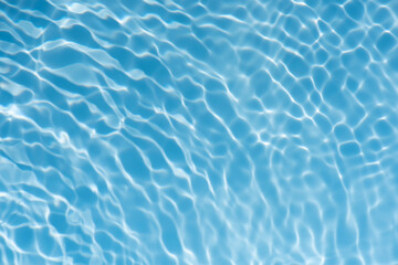 Blue water with ripples on the surface. Defocus blurred transparent blue colored clear calm water surface texture with splashes and bubbles. Water waves with shining pattern texture background.