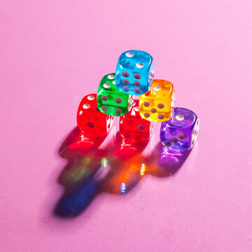 Vibrant dice with colorful shadows on pink background