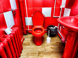 A bright red toilet and sink are featured in a uniquely decorated bathroom with vibrant wall colors...