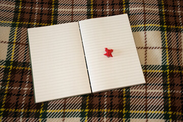 Notebook sewn with Coptic stitch on checkered blanket. Amateur bookbinding. Pages with lines.