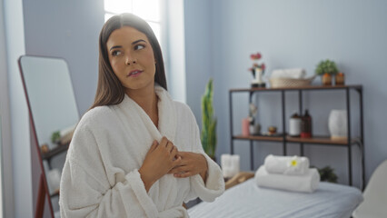 Young woman in white robe at spa seen enjoying a moment of relaxation in a wellness center surrounded by minimalist decor