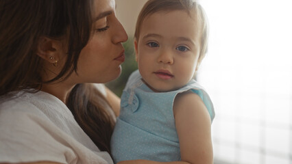 Woman holding infant girl in a home living room setting showcasing family love and togetherness indoors with a tender embrace.