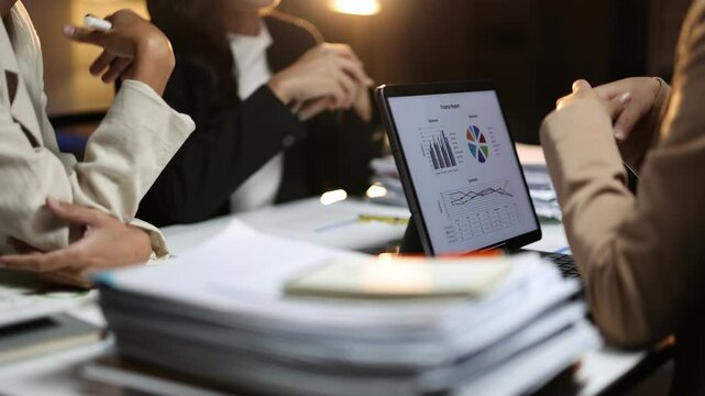 Businesswoman working late analyzing financial report on tablet. Businesswoman working late in the office analyze financial report. Discussion, they navigate data and strategize for future growth.