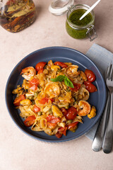 Noodles with shrimps, mussels, tomatoes, onions and capers. Pasta is served with olive oil and pesto sauce. Homemade traditional Mediterranean cuisine. Selective focus, close-up.