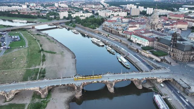 Dresden, Saxony, Germany, steady flight, aerial video view of Dresden historic old town along River Elbe with Augustus Bridge in Front and Carola Bridge in Background - yellow Tram is crossing