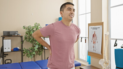 Hispanic man smiling in a rehabilitation clinic with medical equipment in the background