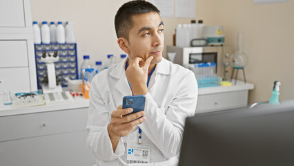 Fototapeta premium A pensive male scientist examines his phone in a laboratory setting, reflecting modern research dynamics.