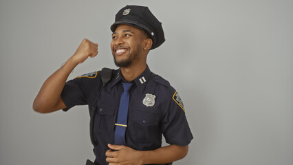 Portrait of a confident african american policeman flexing and smiling against a white background