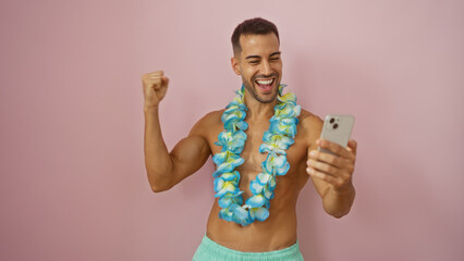 Handsome man with beard wearing hawaiian lei and taking a selfie while smiling against a pink...