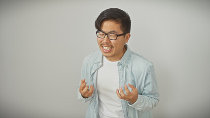 An asian man grimacing with clenched fists against a white background conveying frustration or pain