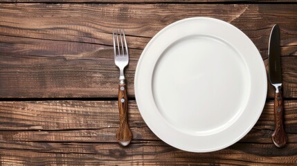 Empty plate, knife and fork on the table. Cutlery, top view.