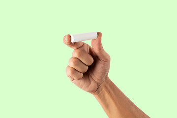 Male hand holding a white battery cell mockup on green background