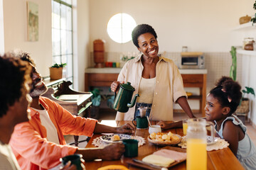 Family breakfast in a Brazilian home: Happy black family sharing a delicious morning meal with drip...