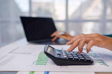 Close up of female hand accountan using a laptop computer and calculator to calculate taxes at desk in the office financial business, calculating accounting online marketing.