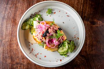 Gourmet dish with a potato base, topped with meat, herbs, radish slices, and caviar, served on a white plate. Perfect for culinary presentations and food photography.