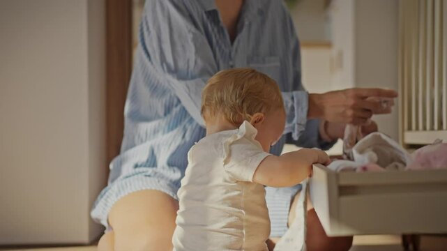 A caring mother puts her home wardrobe in the closets. Together with her child, she puts things in order in the house, sorting clothes. This reflects the concept of raising children through joint work