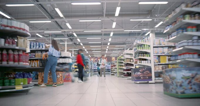 Families and Individuals from Various Backgrounds Shop Together in a Busy Supermarket. Customers Pick Up Canned Food and Packaged Goods while Comparing Prices. Time Lapse Footage