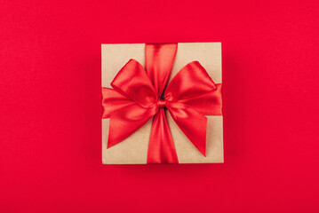 Cardboard gift box with bow on red background. Flat lay. Top view.