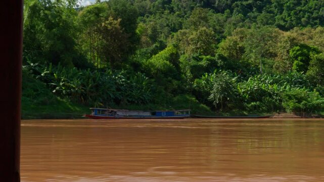 Riverside with green forest background, boat parking on the side, sunny