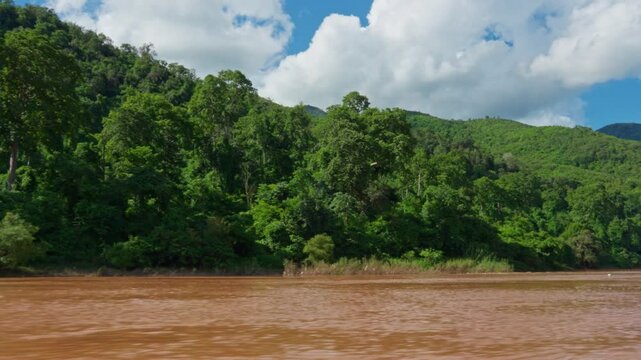 Beautiful view of green hill exposing on the side of river, blue sky, white cloud