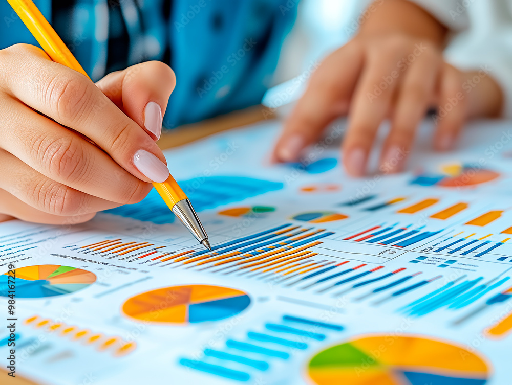 Poster Analyzing various charts and graphs on a document with a yellow pencil.