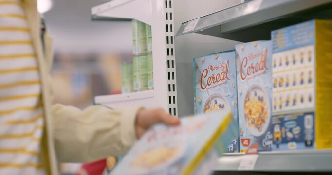 Anonymous Male Taking a Pack of Morning Cereal from the Supermarket Aisle. Close Up on the Box of Food. Person Buying a Breakfast Meal. Shelves are Stocked with Various Products