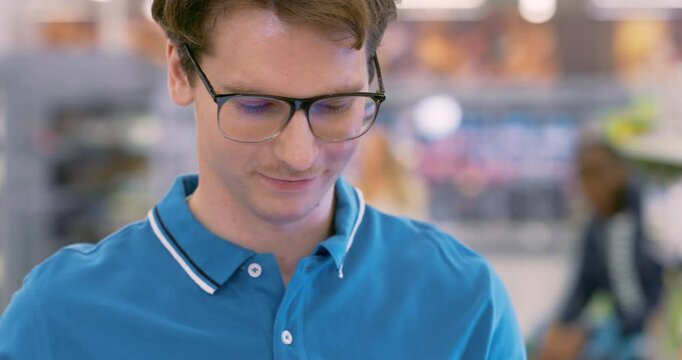 Portrait of a Caucasian Male Supermarket Manager Making an Inventory Review in a Grocery Store. Young Worker Replenishing and Organizing Stock in an Aisle with Canned Food
