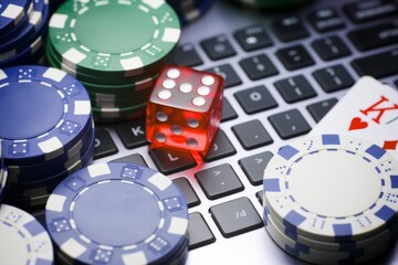 Colorful poker chips and a red die are playfully arranged on a keyboard, embodying the excitement...