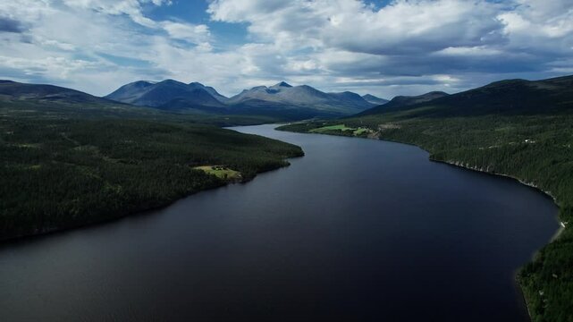 Drone flying over the Atnsj&oslash;en lake, with majestic mountain peaks Storronden, Rondslottet and H&oslash;gronden in Rondane National Park Innlandet Norway.
