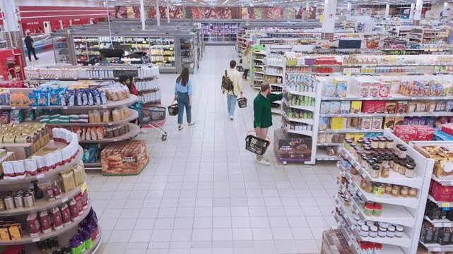 High Angle Footage of a Crowd of Customers From Various Backgrounds Shop Together in a Supermarket. Picking Up Canned Food and Packaged Goods while Comparing Prices and Checking Their Grocery Lists