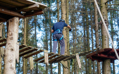 A man is jumping over a tree trunk on a rope course