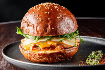 Close-up of a gourmet burger with a sesame bun, melted cheese, and fresh greens on a dark background. Perfect for food photography, restaurant menus, or culinary blogs.