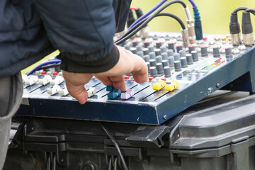 A man is adjusting the knobs on a sound board