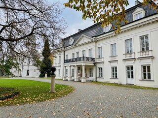 Estate in Radzeev Park. A building with white walls in front of which there is an autumn park.