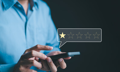 Negative customer review concept. A person use smartphone to give a one-star rating, symbolizing...