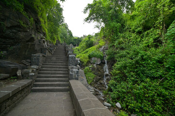 Fototapeta premium Man made stone stairway amidst lush green forest ascending from Lonar crater situated in Maharashtra, India.