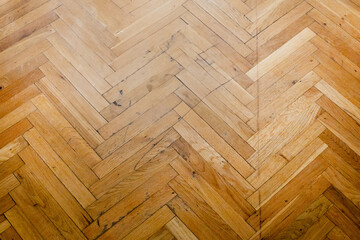 A close-up of a worn and scratched wooden parquet floor needing restoration, symbolizing home...