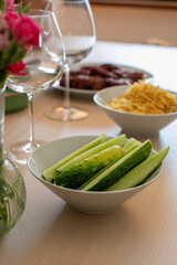 A festive table is set with fresh cucumber slices, snacks, and wine glasses, perfect for a summer gathering or healthy eating concept