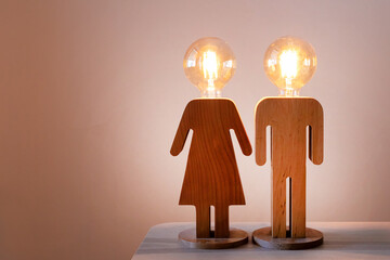 Wooden male and female figures with light bulb heads symbolizing bright ideas and creativity,...