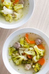 Two bowls of homemade vegetable soup with broccoli, carrots, and meatballs, perfect for a healthy winter comfort meal