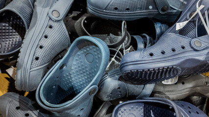 A pile of mismatched plastic clogs highlighting consumerism and waste management issues
