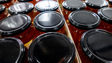 Rows of sealed glass jars filled with honey, ideal for preserving and gifting during the holiday season