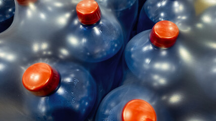 Plastic water jugs with red caps stacked together, highlighting hydration and emergency...