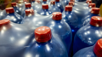 Close-up of multiple blue water jugs with red caps, emphasizing water supply and storage issues...