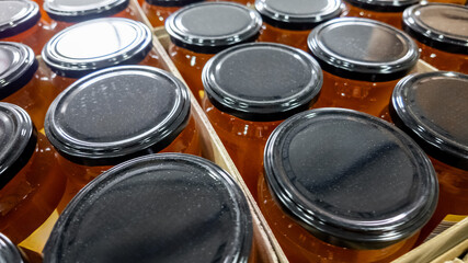 Close-up of neat rows of honey jars with black lids, perfect for concepts of natural food and Christmas gifts